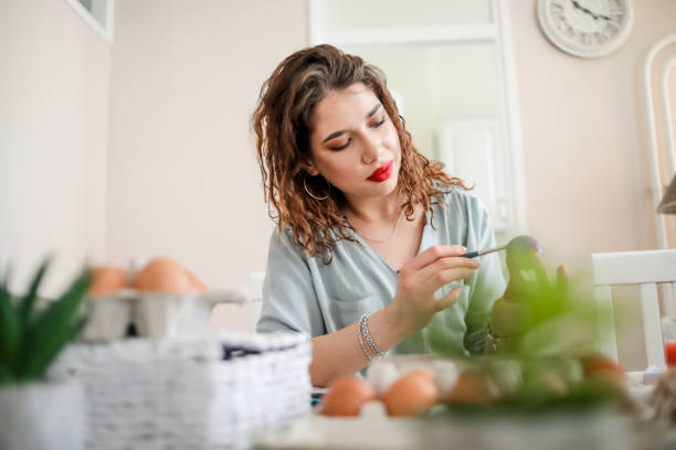 istock Woman decorating easter eggs in home 1214268394