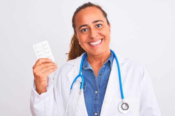 donna medico matura di mezza età che mostra pillole da prescrizione su sfondo isolato con un viso felice in piedi e sorridente con un sorriso sicuro che mostra i denti - toothy smile relaxation white healthcare and medicine foto e immagini stock