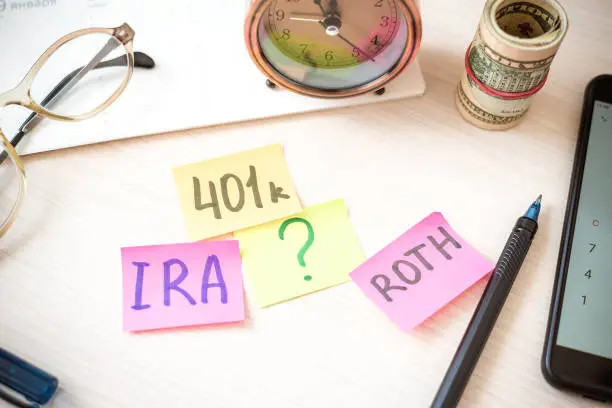 Photo of 401k ira roth on pieces of colorful paper dollars on table. Pension concept. Retirement plans.