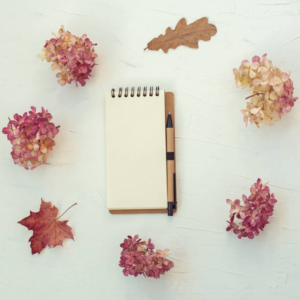 istock Workspace with notebook on white background. Autumn composition with dry flowers and leaves. Flat lay, top view. 1214270534