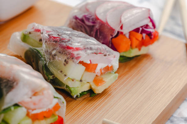 istock Delicious asian dish. Side view of fresh spring rolls with shrimp and vegetables and different sauces served on a wood plate with chop sticks. 1214272927