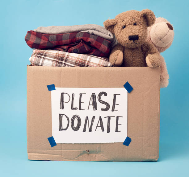 istock large brown cardboard box with the inscription please donate, box is filled with various clothes, toys 1214273748