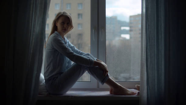 istock Young woman sitting on the window 1214275011