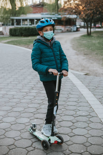 istock Young boy is wearing face mask while playing responsibly outside 1214275038
