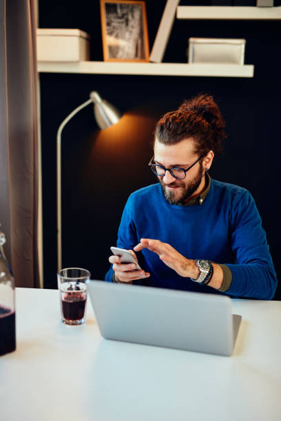 istock Attractive Caucasian bearded entrepreneur sitting in his office, using smart phone and taking a break from work. 1214279448