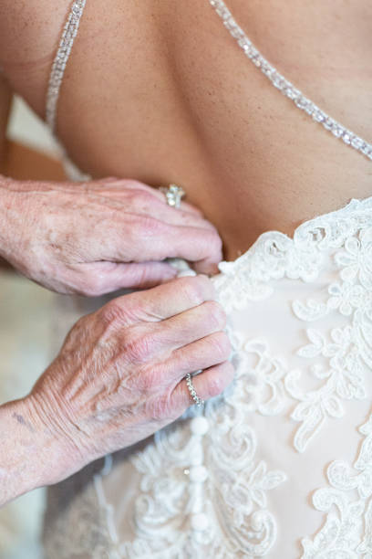 istock Older hands helping bride into dress - close up 1214280033