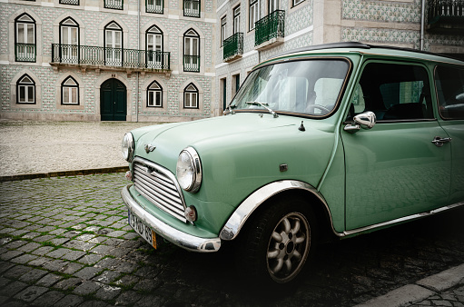 Lisbon, Portugal - February 2, 2019: light green Classic british Austin Mini vintage car parked over the historical screets of Alfama district in Lisbon, Portugal, on february 2, 2019