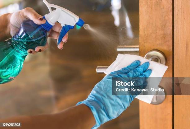 Young Asian Woman Sanitizing Door Handle With Disinfectant Stock Photo - Download Image Now