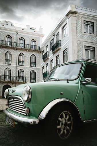 Lisbon, Portugal - February 2, 2019: light green classic british Austin Mini vintage car parked over the historical screets of Alfama district in Lisbon, Portugal, on february 2, 2019