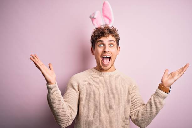 istock Young handsome blond man wearing easter rabbit ears over isolated pink background celebrating crazy and amazed for success with arms raised and open eyes screaming excited. Winner concept 1214281279