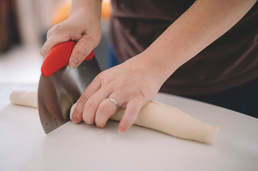 an asian chinese house wife preparing food using rolling pin on flour mixed with eggs on table