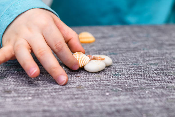 He has a turquoise shirt and picking up a seashell.