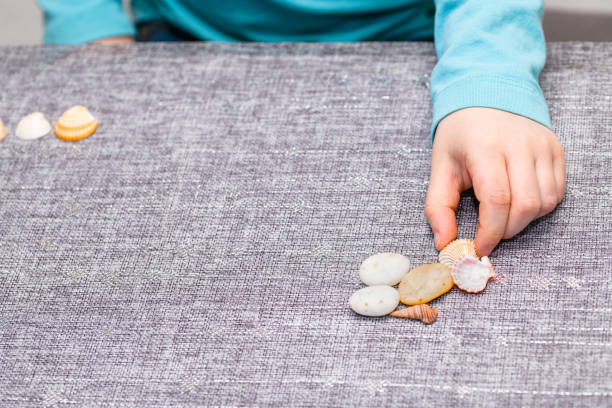 He has a turquoise shirt and picking up a seashell.