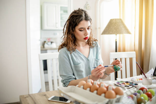 istock Woman decorating easter eggs in home 1214285388