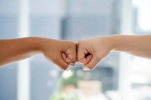 Cropped shot of two unrecognizable businesswomen fist bumping each other inside an office