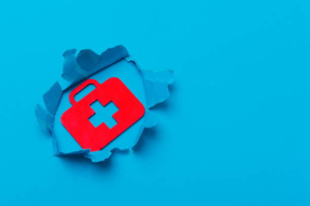 istock First aid bag sign in paper cut hole. Blue background 1214288972