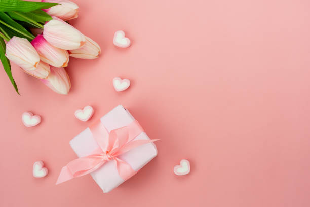 Top view aerial image of decoration Happy motherâs day holiday background concept.Flat lay white present box with flower on modern beautiful pink paper at home office desk.Free space for design. vista superior imagen aérea de la decoración concepto de fondo de vacaciones de día de la madre feliz. caja de regalo blanca plana con flor sobre papel rosa hermoso y moderno en el escritorio de la oficina en casa. espacio libre para el diseño.