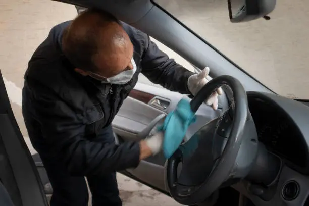 Middle aged Turkish man disinfects his car as a precaution for the pandemic corona virus