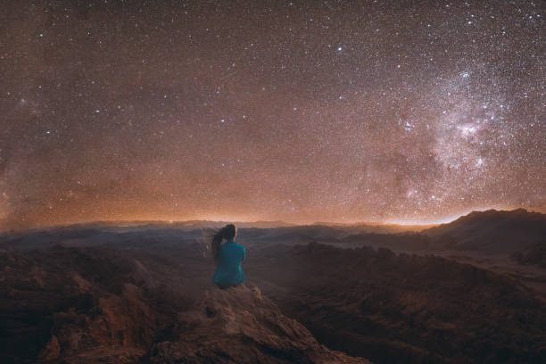 Woman enjoying the scenic view of the million stars above the big canyon at Atacama desert, Chile Silhouette of woman tourist with long hair feeling freedom and happiness looking at the night star sky and Milky Way above the Moon Valley canyon in Atacama desert, South America, Chile atacama desert photos stock pictures, royalty-free photos & images