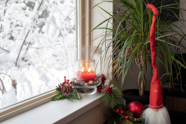istock Christmas candle burns on windowsill inside house 1214295612