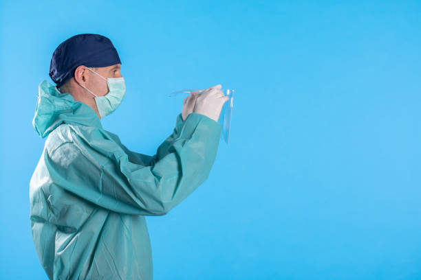 istock doctor with protective mask and cap putting on protective gloves against coronavirus. Personal protective medical equipment. 1214295626