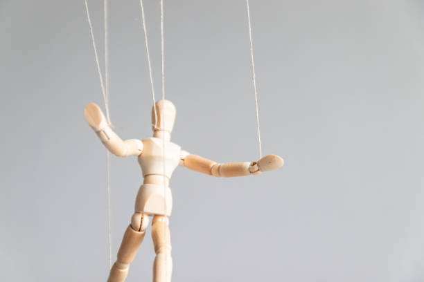 istock Human control concept. Wooden puppet doll on the clothesline on a gray background with copy space. 1214296242
