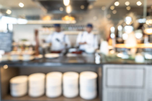 istock Buffet at hotel restaurant interior blur background with blurry open kitchen counter bar of food catering service business with chef staff cooking for breakfast, lunch or dinner meal 1214298547