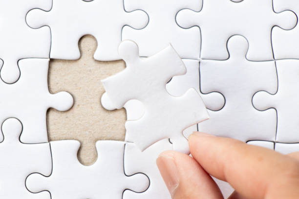 istock Closed up background of white plain jigsaw with hand that hold missing piece to match or fulfill 1214299755