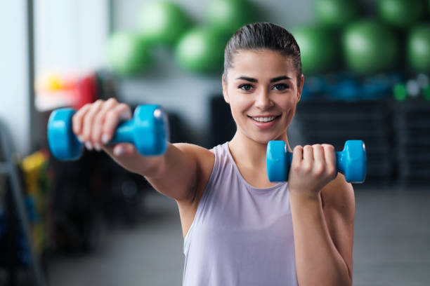 A beautiful athletic young brunette woman in sportswear trains in the gym. stock photo