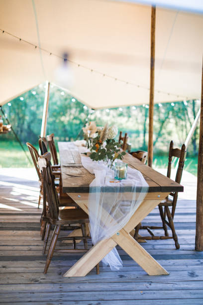 istock Wedding or dinner reception table, decorated in rustic style, outdoors in stylish tent. Reception on open air, rustic wedding 1214299979
