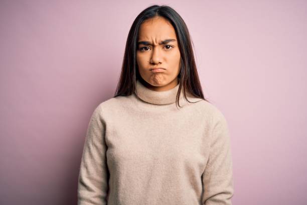 young beautiful asian woman wearing casual turtleneck sweater over pink background skeptic and nervous, frowning upset because of problem. negative person. - frowning imagens e fotografias de stock
