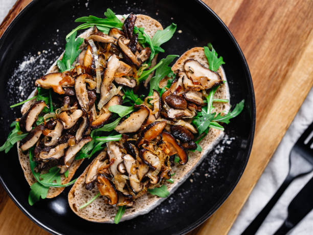 widok z góry na dwie wegańskie kanapki ze świeżą rukolą, smażonym grzybem shiitake i cebulą szalotką. - appetizer bruschetta meal lunch zdjęcia i obrazy z banku zdjęć