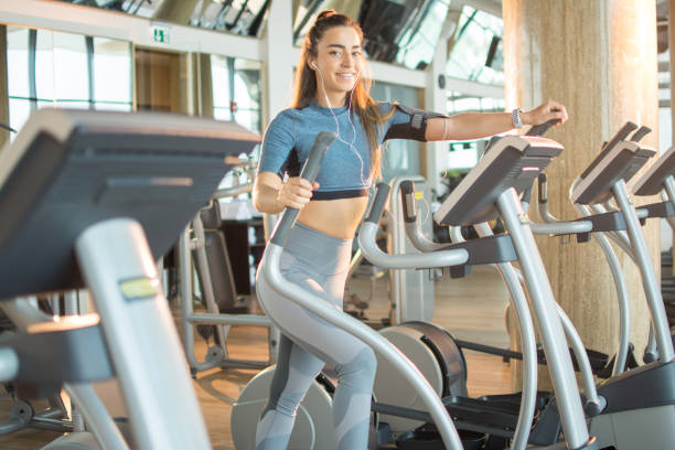 istock Fit young woman exercising on a cardio training elliptical machine at gym 1214302156
