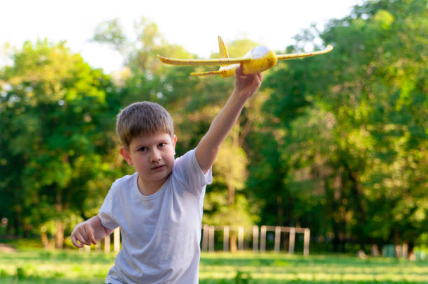 istock Young boy playing with toy glider in park on summer day at sunset. 1214303974