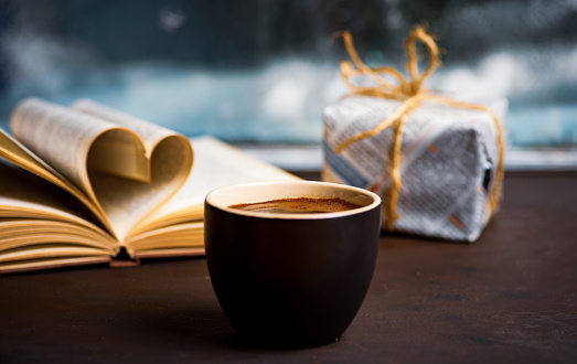 Cup of coffee with reading material by the window at home