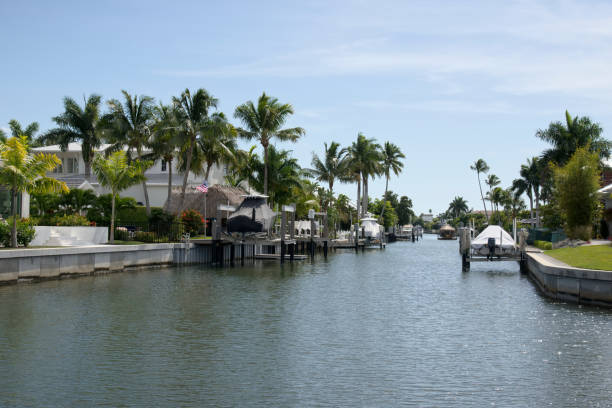 Royal Palms line the canal connecting this luxury residential area to the gulf of mexico with the boats all wrapped up on their lifts, everything neat and tidy and a tourist boat filled with sightseers coming up the center of the canal