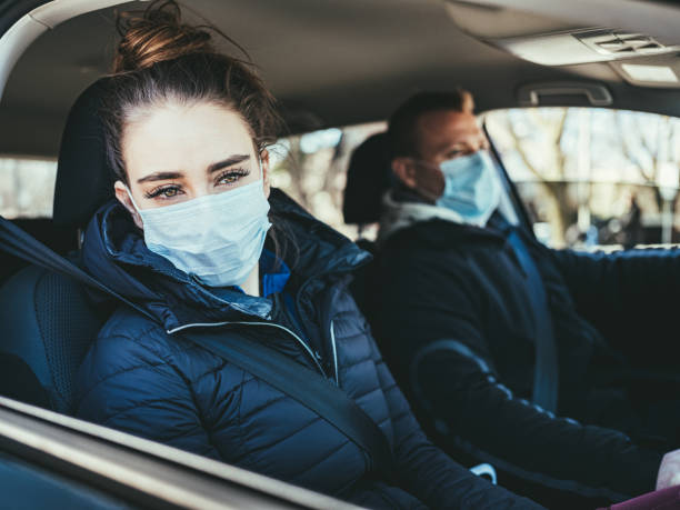istock COVID-19, Young couple wearing disposable face mask while driving 1214305468