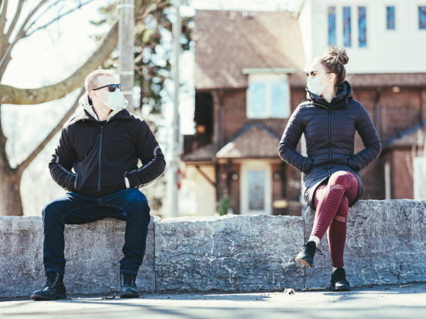 COVID-19, Young couple meeting outside Young couple wearing disposable face masks meeting in outdoors. Mask is Disposable Earloop Face Mask with Filters against Bacteria. social distancing stock pictures, royalty-free photos & images