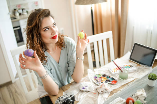 istock Woman decorating easter eggs in home 1214310275