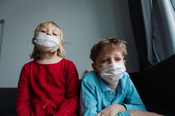 istock kids with masks, quarantine at home, virus or infection 1214313569
