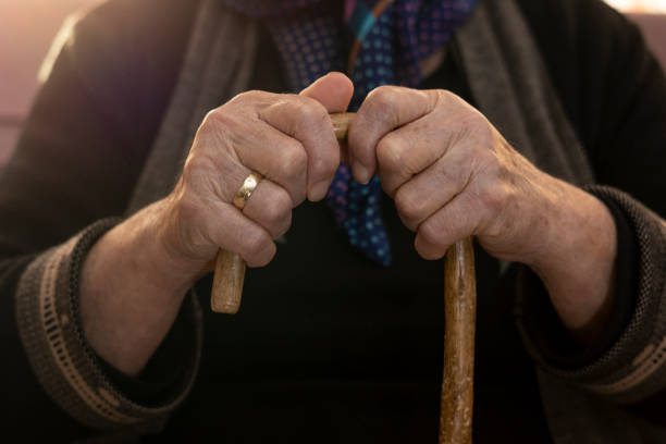 istock Old human hands holding an old walking stick 1214315244
