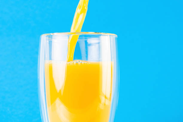 istock Full glass of orange juice on a blue background 1214315464