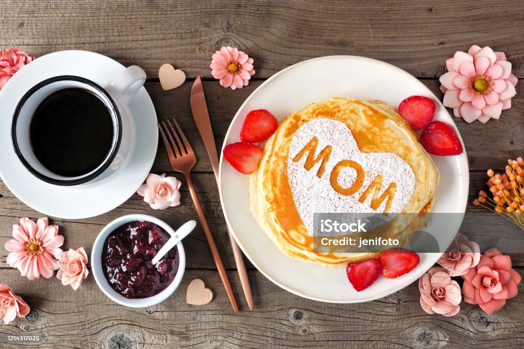 Mothers Day breakfast pancakes with heart shape and MOM letters, overhead view table scene on rustic wood Pancakes with heart shape and MOM letters. Mothers Day breakfast concept. Overhead view table scene with a rustic wood background. Mother's Day Stock Photo