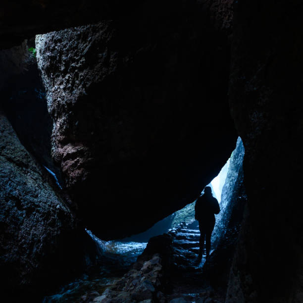 istock Woman Hikes Under Boulder in Cave Area 1214318071
