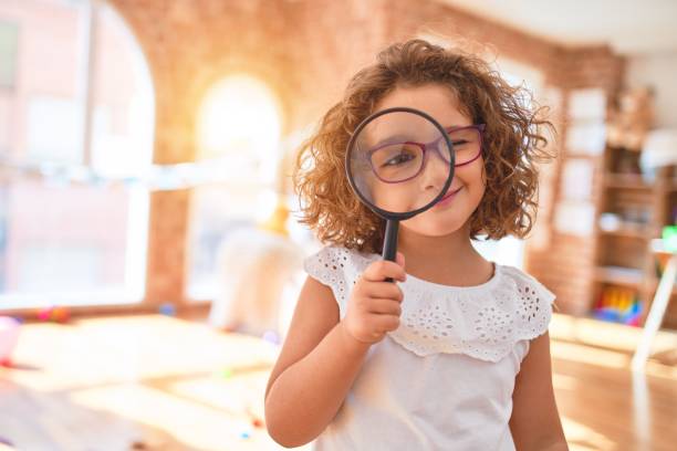 hermoso niño de pie usando gafas usando loupe en el jardín de infantes - curiosity searching discovery home interior fotografías e imágenes de stock