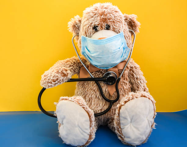 coronavirus covid-19 and pollution protection concept. teddy bear doll wearing mask and phonendoscope on yellow background, copy space - flu virus cold and flu swine flu epidemic imagens e fotografias de stock