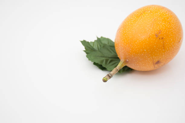 Close-up of yellow passion fruits and halved passion fruits showing juicy pulp and seeds. Bright minimalist setup highlighting the tropical fruit's texture and color.