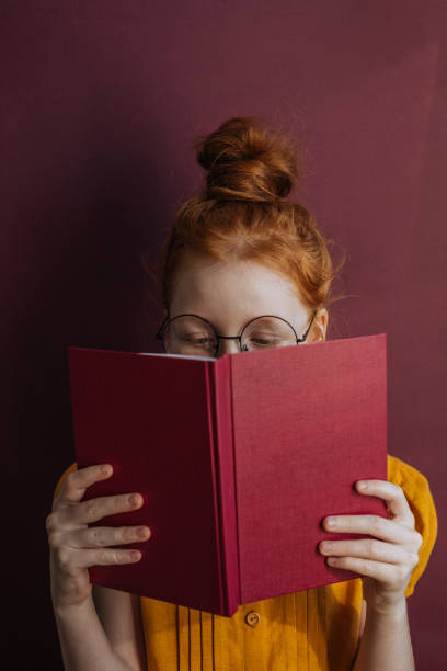 istock Red-haired girl with glasses and a book 1214322457