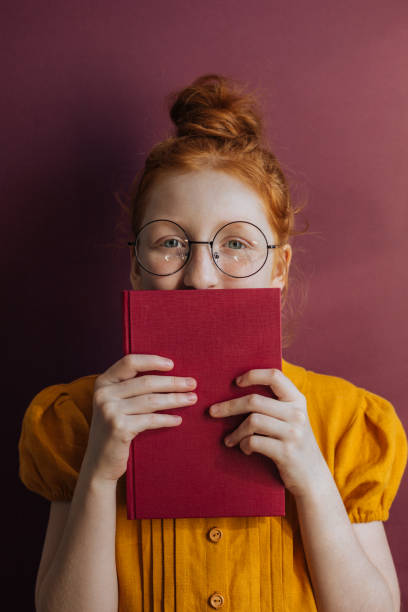 istock Red-haired girl with glasses and a book 1214322467