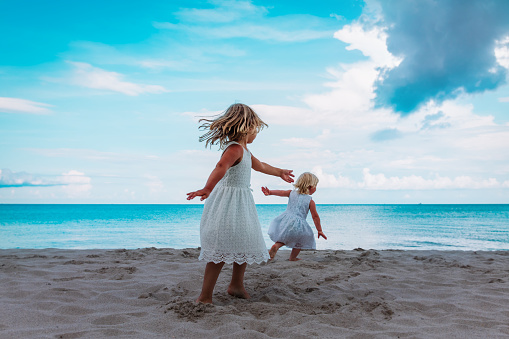 cute little girls dance play at summer beach vacation